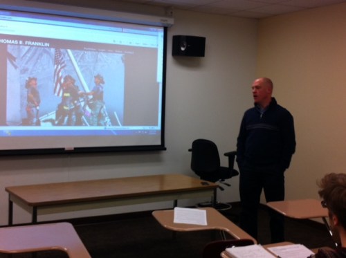 Tom in a darkened classroom talking to journalism students about his photograph